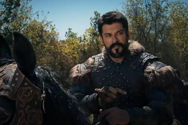 a man in armor holding a sword and standing next to a horse